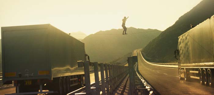 Faith Dickey walks across a slackline between two speeding volvos